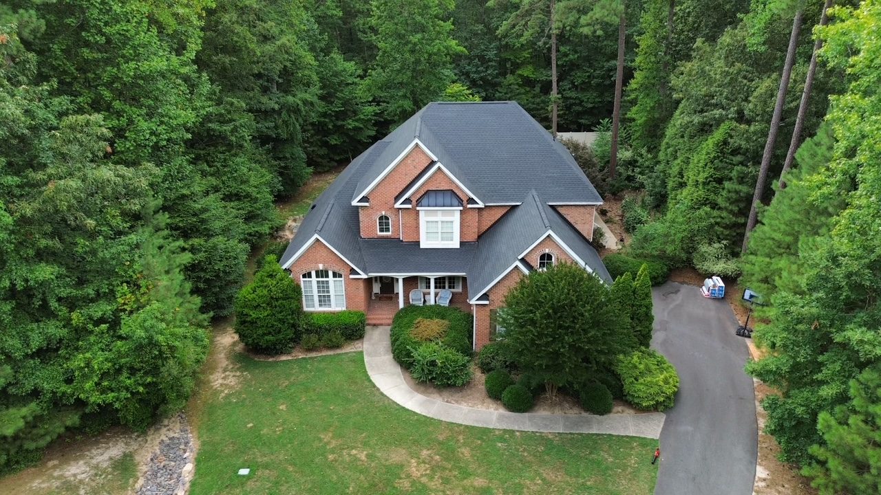 Aerial view of a brick home with a newly installed charcoal shingle roof