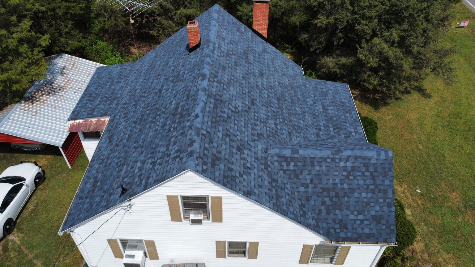 New blue-gray shingle roof on a two-story white farmhouse